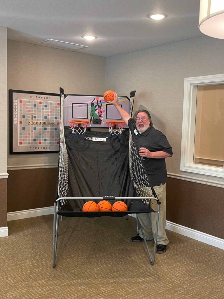 Charlie Johnson is about to dunk an inside small basketball into a hoop. He has a big smile while taking a break from the spring cleaning.