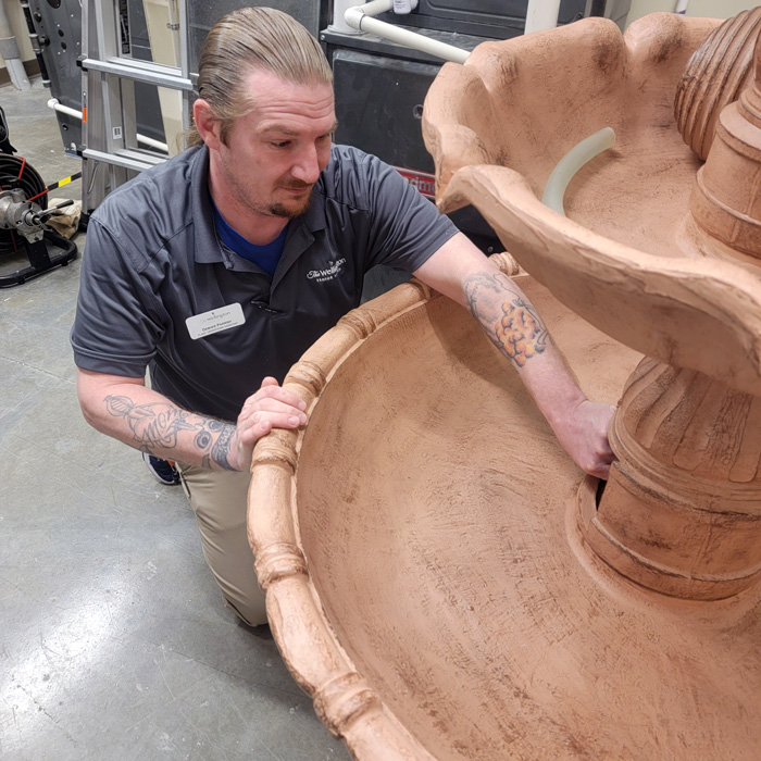 Maintenance team member preparing large decorative fountain for spring at senior living community