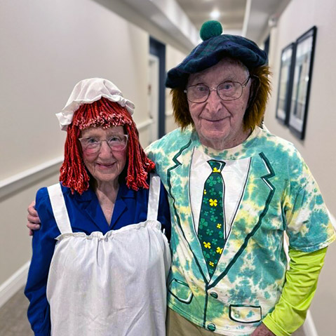 A senior man and woman show off their colorful Halloween costumes during a community event.